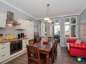 Una cocina moderna con armarios blancos, una mesa de comedor de madera y un sofá de cuero rojo.