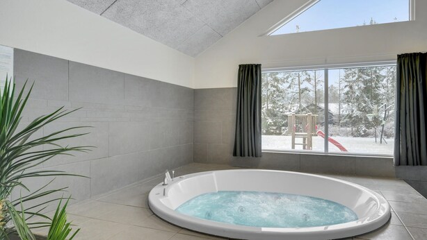 Een moderne badkamer met een vrijstaand bad, grote ramen en uitzicht op een besneeuwde omgeving.