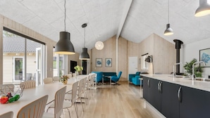 Een moderne keuken met een centraal eiland, houten vloer en hanglampen.