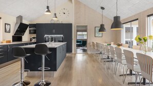 Een moderne keuken met een centraal eiland, zwarte barkrukken en hanglampen.