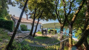 A hammock in a lush garden with a white house and a view of a lake. - 2 bedroom nice apartment in Krnica (Krnica)