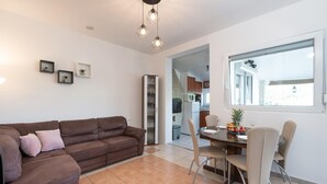 A living room with a brown sofa, a dining table with chairs, and a window with a view. - 2 bedroom nice apartment in Krnica (Krnica)