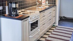 A kitchen with white cabinets, a stove, an oven, a coffee maker, and a microwave. - 2 bedroom awesome home in Sölvesborg (Sölvesborg)
