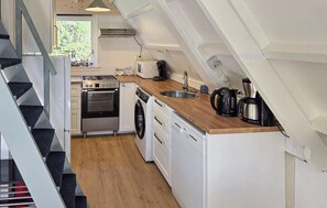 A kitchen with a stove, oven, washing machine, and coffee maker.
