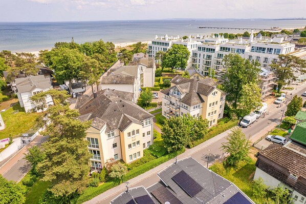 Un quartier résidentiel en bord de mer, avec des bâtiments modernes et traditionnels, une plage et un pont en arrière-plan.