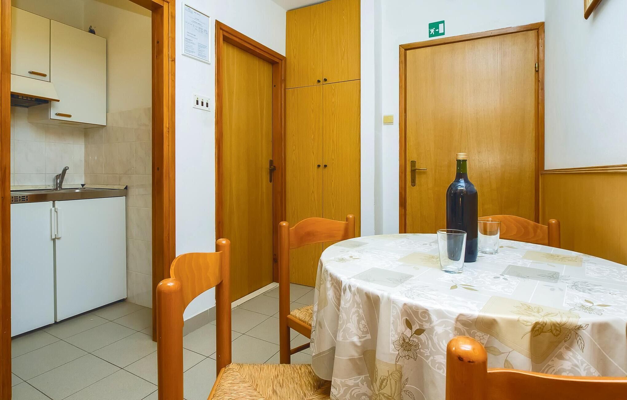 Ein Essbereich mit einem runden Tisch, Stühlen, einer Flasche und einem Glas.