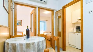 A room with a round table, chairs, a bed, and a kitchenette.