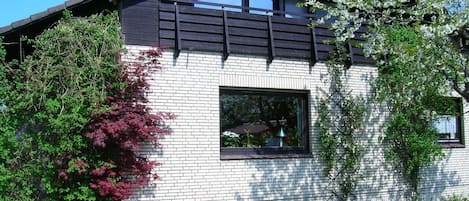 A modern house with a brick facade, a large window, and a balcony.