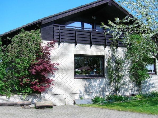 A modern house with a brick facade, a large window, and a balcony.
