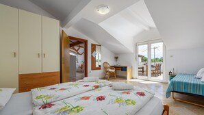 A bedroom with a large bed, a desk, and a chair, with a view of the outdoors through a sliding door. - Nice apartment in Porec (Porec)