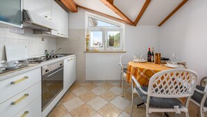 A kitchen with white cabinets, a stove, and a window overlooking a garden. - Nice apartment in Porec (Porec)