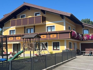 Ein mehrstöckiges Hotel mit Balkon, Kinderspielbereich und Parkplatz.