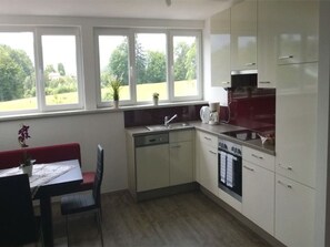 A kitchen with a dining area, large windows, and a dishwasher.