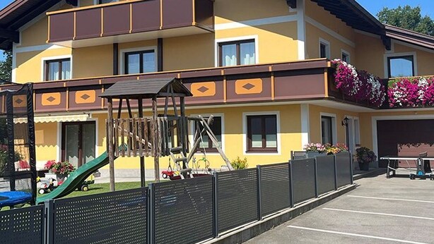 A multi-story building with balconies, a playground, and a parking area. - Apartment Schafberg - Gästehaus Wienerroither (Mondsee)