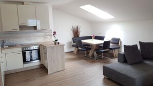A modern kitchen with a dining area and a sofa. - Apartment Schafberg - Gästehaus Wienerroither (Mondsee)