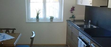A kitchen with a window, a sink, cabinets, and a stove.