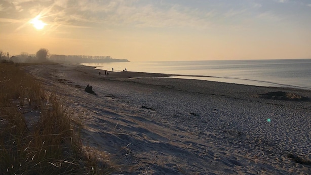 Une plage avec un ciel dégagé, où l’on peut admirer le coucher ou le lever du soleil.