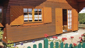 Une cabane en bois dotée d’une grande fenêtre, d’une porte et d’un petit espace porche.