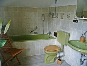 A bathroom with a green bathtub, a toilet, and a sink. - Vacation home 'Weitblick' - Holiday home Weitblick (Edertal)