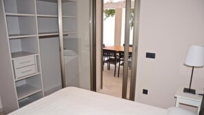 A bedroom with a bed, a wardrobe, a desk with a lamp, and a view of an outdoor patio with a table and chairs. - 4 bedroom awesome home in Palma de Mallorca (Palma de Mallorca)