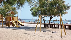A beach playground with a slide and swings, surrounded by trees and beach umbrellas. - 4 bedroom awesome home in Palma de Mallorca (Palma de Mallorca)