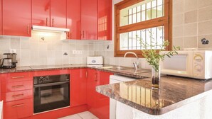 A kitchen with red cabinets, a built-in oven, a microwave, and a sink. - Awesome home in Calonge (Calonge)