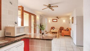 A compact kitchen with a microwave, a red cabinet, and a dining area with a table and chairs. - Awesome home in Calonge (Calonge)