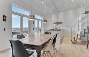 Une cuisine moderne dotée d’un îlot central, de grandes fenêtres et d’un escalier.