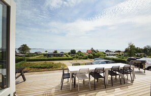 Une terrasse avec une table et des chaises donnant sur un quartier résidentiel et un plan d’eau.