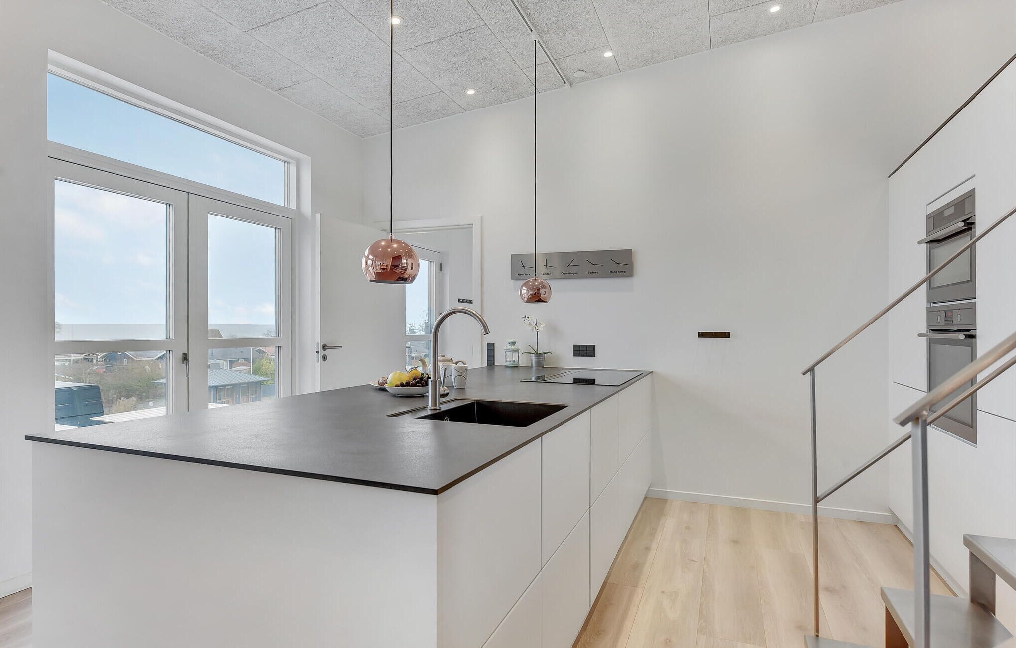 Una cocina moderna con una isla grande, electrodomésticos de acero inoxidable y vistas a la ciudad.