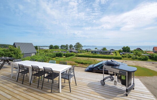 Une terrasse avec une table et des chaises, un barbecue et une vue sur les maisons et l’eau.