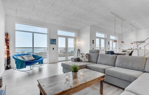 A spacious living room with a grey sofa, a blue rocking chair, and a wooden coffee table. - Nice home in Sjølund with sauna (Sjølund)