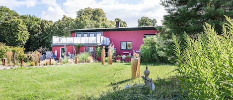 Un edificio rojo con balcón, rodeado de vegetación y árboles.