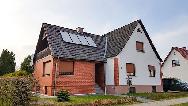 Ein modernes, zweistöckiges Haus mit Satteldach, Solaranlage und Ziegelaußenwand.