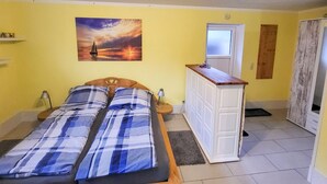 Ein Zimmer mit zwei Betten, einem kleinen Schreibtisch, einem Sonnenuntergangsbild und einer Tür mit Sandstrahlglas.