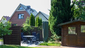 Ein Garten mit Terrasse, Holzschuppen und Backsteinhäuschen.