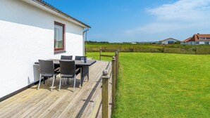 Een wit gebouw met een terras en zitgedeelte buiten.