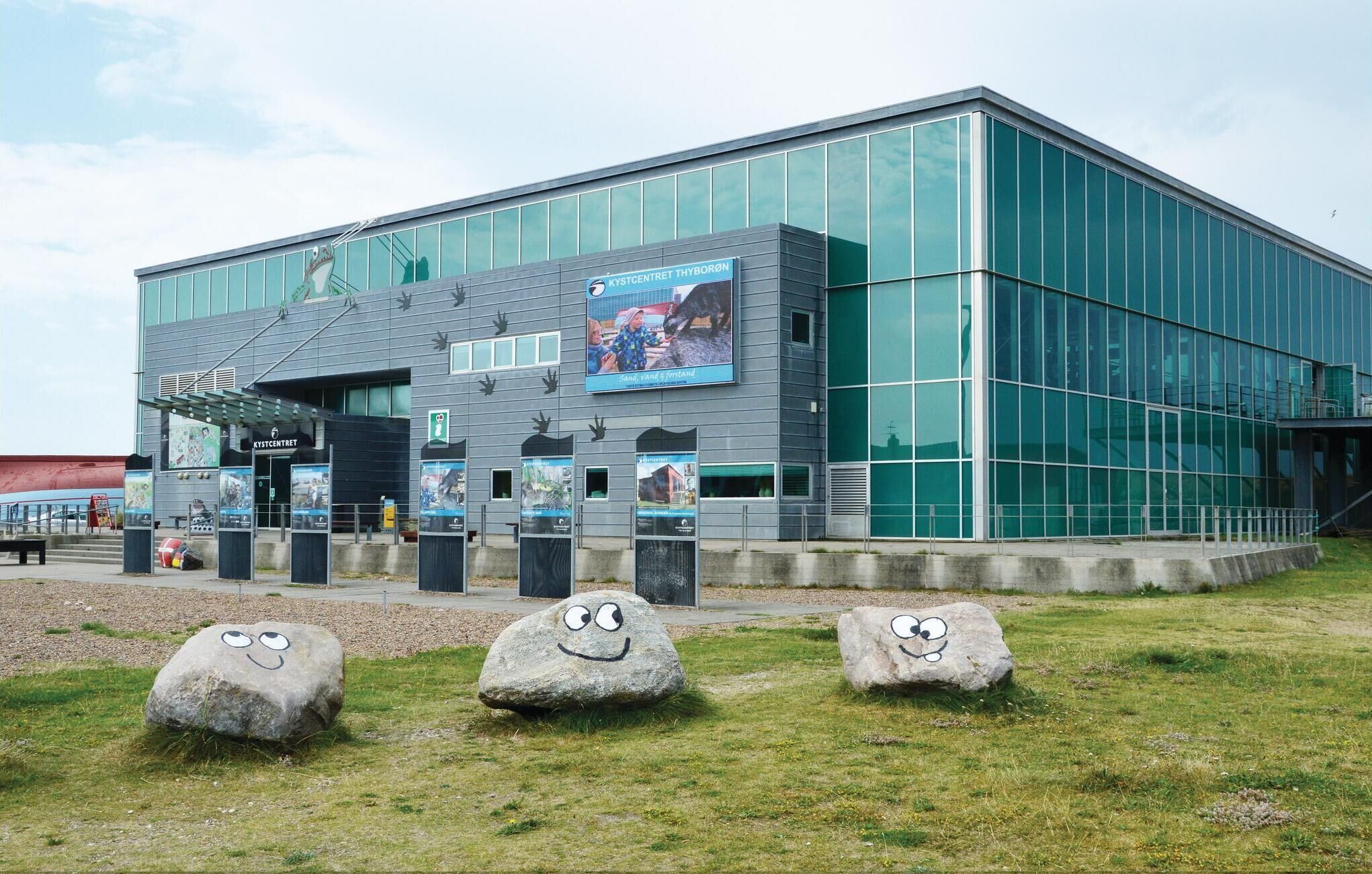A modern building with large glass windows and a sign reading "KYSTCENTRET THYBORØN".