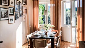 Ein Esszimmer mit Tisch für vier Personen, gerahmten Bildern an der Wand und einem Fenster mit Vorhängen.