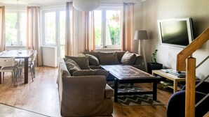 Ein Wohnzimmer mit einer Couch, einem Couchtisch, einem Fernseher und einem Essbereich mit Stühlen und einem Tisch.