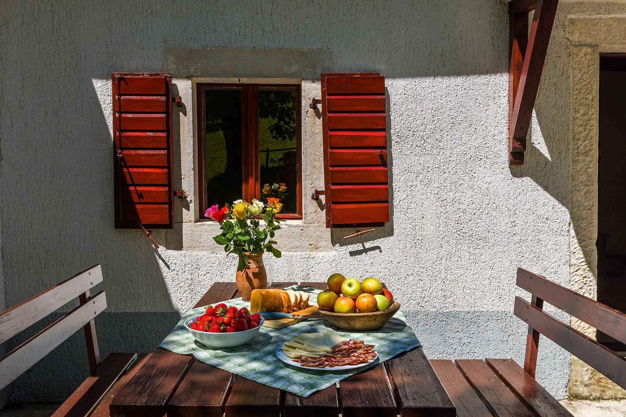 Une table avec des aliments, un vase rempli de fleurs et une fenêtre avec des volets.