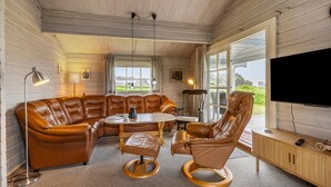 A cozy living room with a leather sectional sofa, a round coffee table, and a wooden chair. - 3 bedroom amazing home in Egernsund (Egernsund)