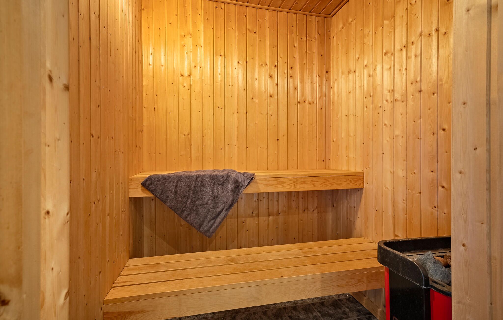 A wooden sauna with benches and a towel rack.