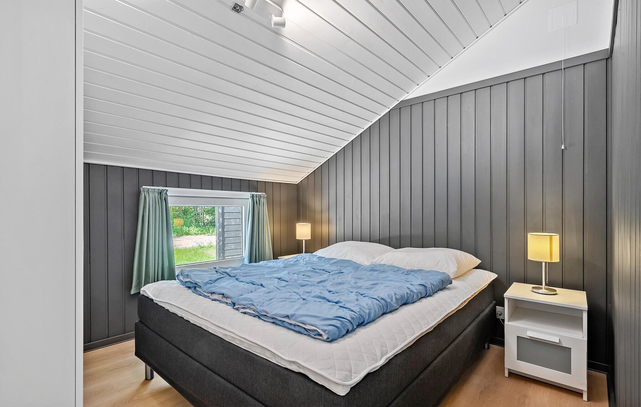 Una camera da letto con un letto, comodini e una finestra con tende.