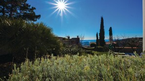 A garden with cypress trees, a clear blue sky, and a distant view of a body of water. - Amazing home in Izola (Izola)