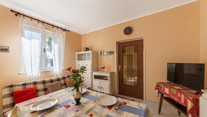 A dining area with a table set for two, a sofa, a television, and a cabinet. - Cozy home in Labin with kitchen (Labin)