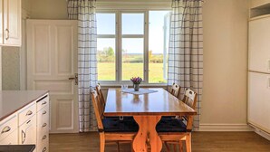 Un comedor con una mesa de madera, seis sillas y una ventana con cortinas.