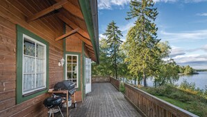 Une cabane en bois dotée d’une terrasse offrant une vue sur un lac, avec un barbecue et une lanterne.
