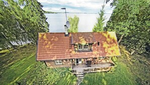 Une maison à deux étages, avec un toit recouvert de tuiles rouges, un balcon et une vue sur un lac.