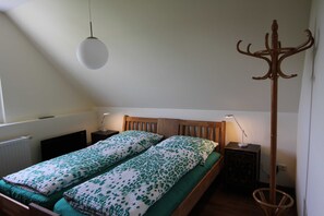 Un dormitorio con una cama de madera, dos mesitas de noche, una lámpara de pie y un perchero.